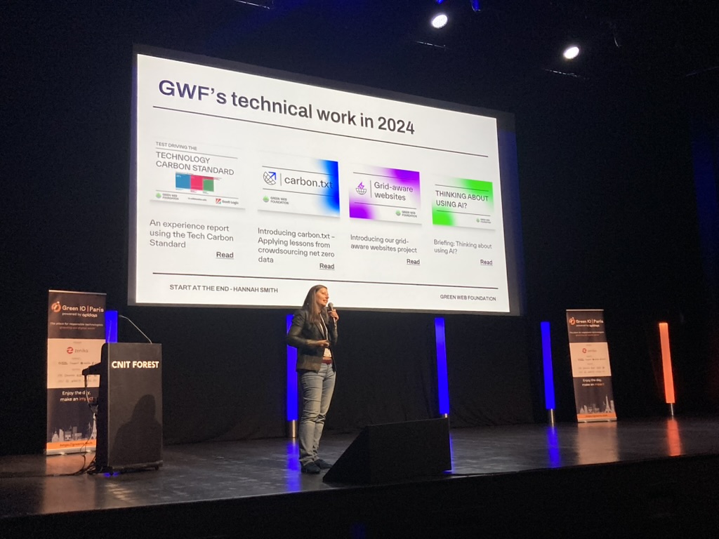 Hannah Smith on stage at Green IO Paris, mentioning the Green Web Foundation's technical fork in 2024: the Tech carbon standard report, carbon.txt, grid-aware websites,  and our report on the environmental impact of AI